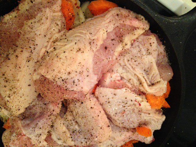 chicken in pan on top of carrots and onions
